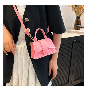 Pink quilted crossbody bag with top handle worn with a black blazer and white skirt