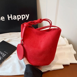 Sac seau en daim rouge avec poignée tressée et breloque sur un ensemble élégant