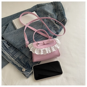 Dettaglio mini borsa a tracolla rosa con fiocco 3D e rifiniture in pizzo bianco eleganti