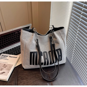 Detail of canvas tote bag with black MEADDA leather patch and silver chain strap