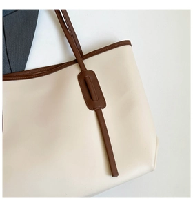 Macro shot of cream tote bag upper edge with dark brown contrast handle and stitching