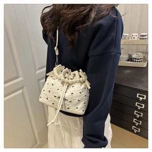 Détail du sac seau blanc avec broderie nœuds noirs et anse élégante en perles
