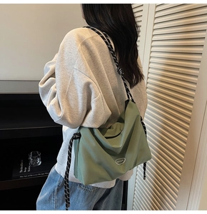 Detailed view of green crossbody bag featuring striped rope strap and minimalist brand logo