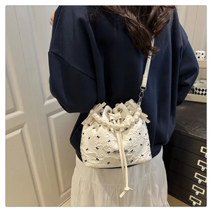 Détail du sac seau blanc avec poignée en perles et imprimés nœuds porté par un modèle