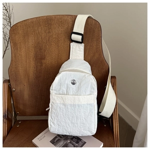 Detail of waterproof nylon chest bag in beige with metal logo and adjustable strap