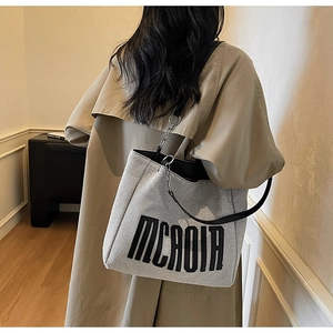 Detail of grey canvas tote bag with black letter print and metal chain leather strap