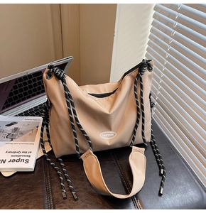 Dettaglio borsa a tracolla in nylon beige con tracolla a righe e spallina morbida