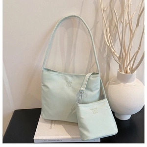 Detail view of light green shoulder bag and matching mini pouch set with embroidery