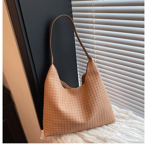Detailed view of caramel leather woven texture on a large hobo shoulder bag