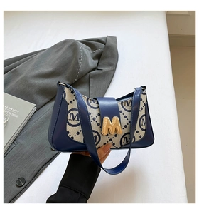 Detail of vintage monogram canvas bag with golden M buckle and navy leather trim