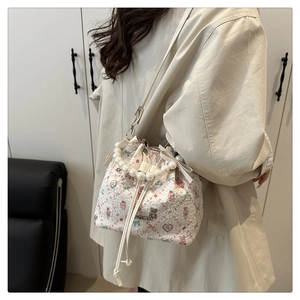 Détail d'un sac seau floral avec poignée en perles et motif ours porté