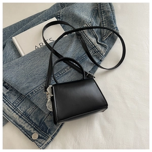 Vista piatta di una mini borsa nera su letto bianco con giacca di jeans blu