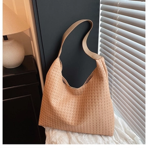 Detailed view of beige woven leather texture on a minimalist hobo shoulder bag