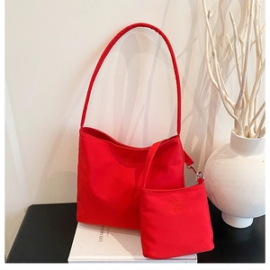 Red nylon bucket bag detail with embossed lettering and matching small coin pouch accessory