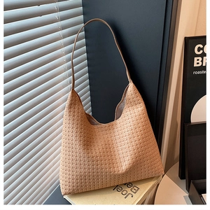 Detail of light khaki woven shoulder bag with intricate cross-weave texture and shadow