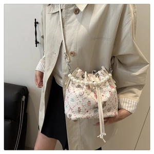Détail du sac seau floral avec poignée en perles, nœud décoratif et fermeture coulissante