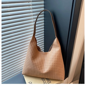 Detailed view of light brown woven texture and leather strap on a hobo shoulder bag
