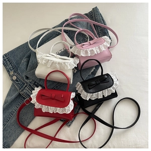 Dettaglio flat lay di mini borse con fiocco in rosso, nero, bianco e rosa con pizzo