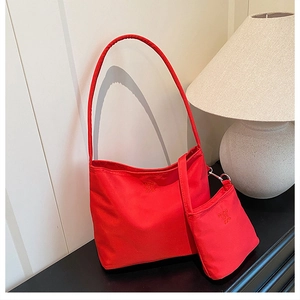Detail of red nylon shoulder bag featuring embossed text and matching coin purse