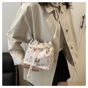 Détail du sac seau floral avec poignée en perles et tissu texturé sur modèle