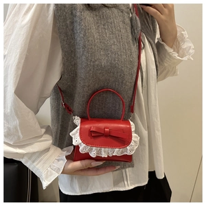 Detail of red mini handbag with white lace trim and bow decoration on the flap