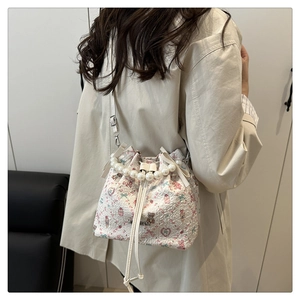 Détail du sac seau à cordon avec anse en perles, motif ours fleuri et nœuds décoratifs