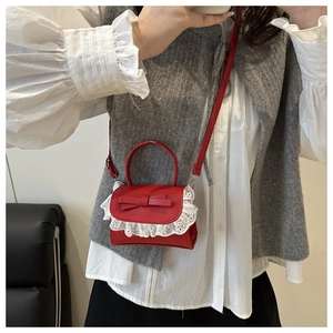 Detail of red mini handbag with sweet bow decoration and delicate white lace trim edges
