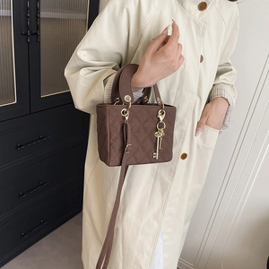 Brown quilted mini crossbody bag with gold key charm and detachable shoulder strap