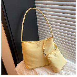 Detail of yellow nylon shoulder bag featuring 'enjoy by it' embroidery and small coin pouch