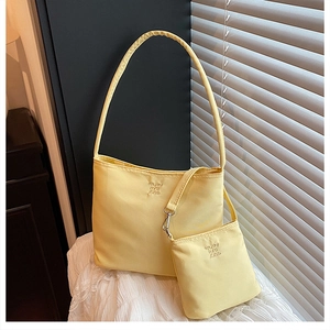 Close-up of yellow nylon tote with embossed enjoy by zz text on white lace fabric