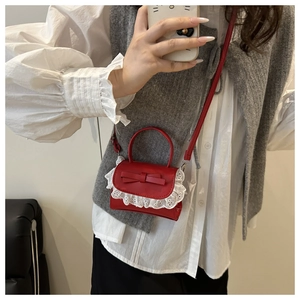 Selfie allo specchio della mini borsa a tracolla rossa con fiocco e dettagli in pizzo