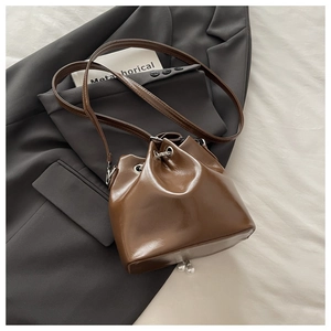 Detail of vintage brown bucket bag with pearl pendants and silver chain on textured fabric