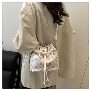 Détail du sac seau blanc à fleurs avec poignée en perles et motif d'ours en peluche