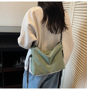 Dettaglio borsa a tracolla in nylon verde con tracolla a righe indossata dal modello