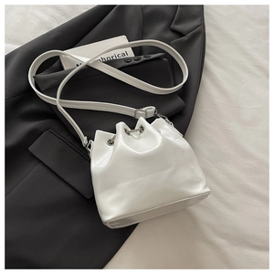 Macro detail of white oil wax leather bucket bag with silver chain and drawstring closure