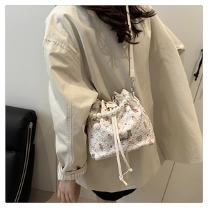 Détail du sac seau à fleurs avec poignée en perles, motifs cartoon et longue bandoulière