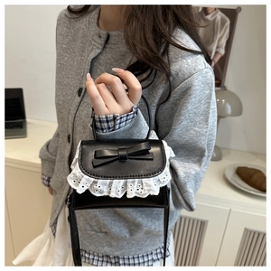 Dettaglio mini borsa nera con bordo in pizzo e fiocco su un maglione grigio operato