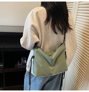 Dettaglio della borsa a tracolla in nylon verde con tracolla a corda e logo del marchio