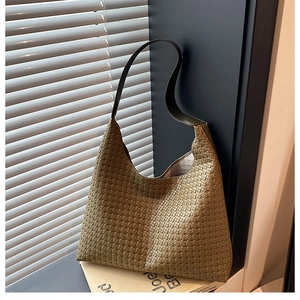 Detail of olive green woven hobo bag showing intricate texture and leather shoulder strap