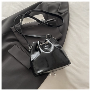 Detail view of black oil wax leather bucket bag with elegant white pearl charms