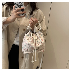Détail du sac seau floral avec poignée en perles, nœud papillon et motifs mignons