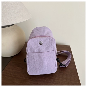Close-up of lavender textured chest bag with metallic M logo and nylon strap