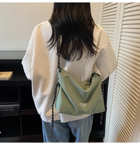 Dettaglio di una borsa a tracolla in nylon verde chiaro con tracolla in corda bicolore su modella