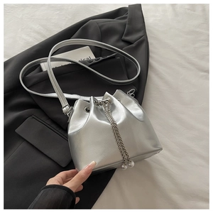 Detail of silver oil wax leather bucket bag featuring metal chain and pearl drawstring