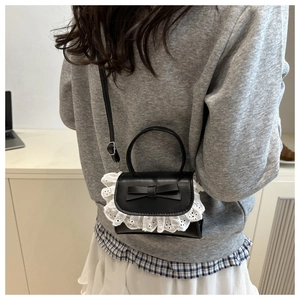 Detail of black PU crossbody bag featuring a sweet bow and delicate white lace trim detail