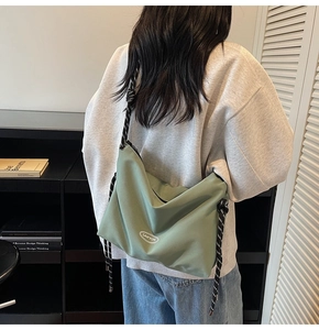 Dettaglio della borsa tote in nylon verde con tracolla decorativa con nodi bianchi e neri