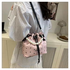 Détail du sac seau rose à anse perle avec motifs nœuds et bandoulière réglable