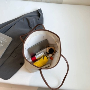 Large cream tote bag with brown straps showing spacious interior for laptop and daily items