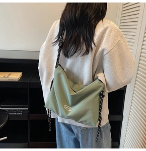 Dettaglio borsa a tracolla in nylon verde con spallina intrecciata su un modello