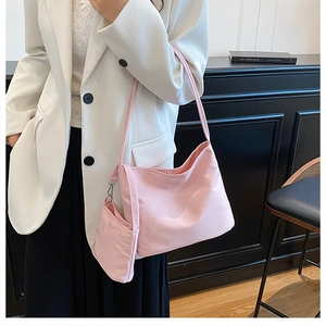 Detail of light pink nylon tote bag with matching detachable pouch on white suit model
